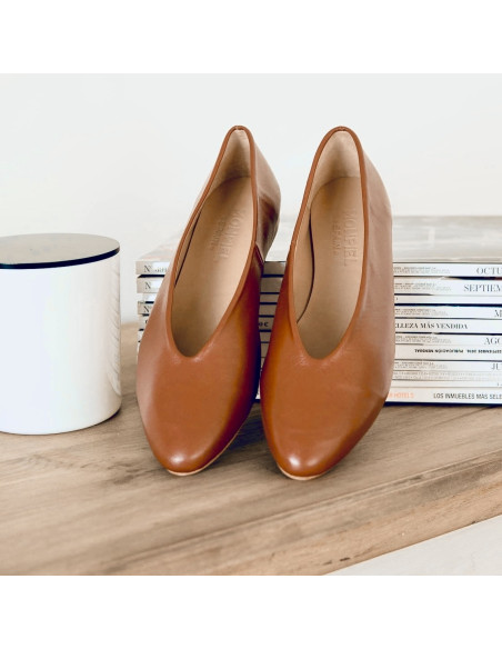 Flat leather ballerina in leather color, perspective view with the heel resting on magazines - MONPIEL Flat leather ballerina in leather color, perspective view with the heel resting on magazines - MONPIEL