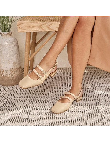 Merceditas Lolina ouvertes à l'arrière couleur crème, jambes croisées, pied posé sur un tapis - MONPIEL Merceditas Lolina ouvertes à l'arrière couleur crème, jambes croisées, pied posé sur un tapis - MONPIEL
