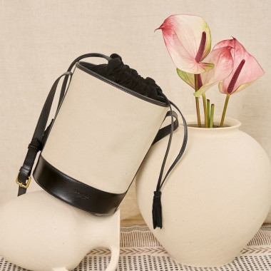 Borsa a secchiello in canvas e pelle di colore nero, vista frontale, appoggiata su un muro - MONPIEL 2