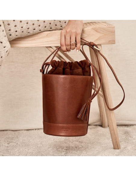 Sac rond en cuir couleur Havana, petite taille, vue frontale, tenu par la poignée courte - MONPIEL