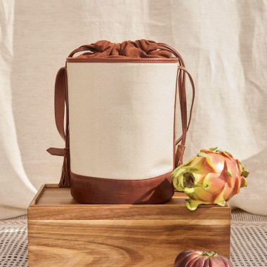 Canvas and leather bucket bag in black, front view, resting on a wall - MONPIEL 2