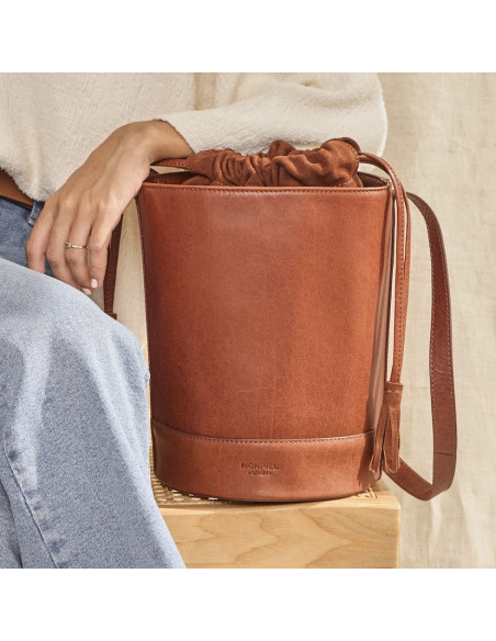 Bolso redondo en forma de cubo de piel en color habana con vista frontal y brazo apoyado - MONPIEL