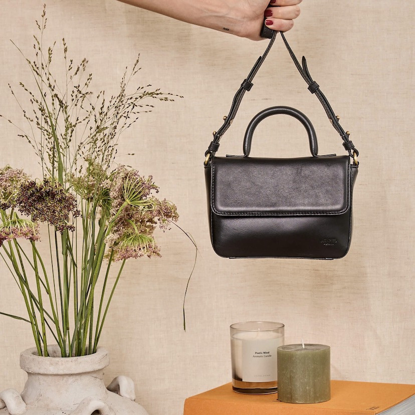 Bolsa de couro pequena Armado em preto, vista frontal segurada pela alça longa, com detalhes de velas - MONPIEL