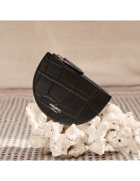 Portafoglio in pelle a forma di mezzaluna, colore nero, vista frontale, appoggiato su una roccia - MONPIEL Portafoglio in pelle a forma di mezzaluna, colore nero, vista frontale, appoggiato su una roccia - MONPIEL