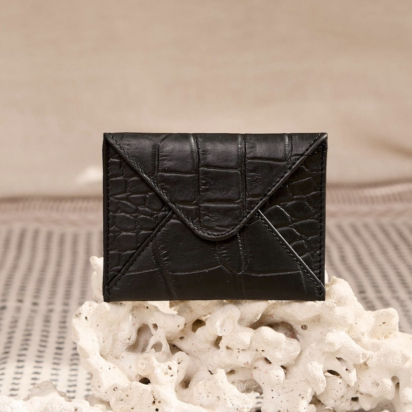 Black leather envelope cardholder, front view, resting on a rock - MONPIEL