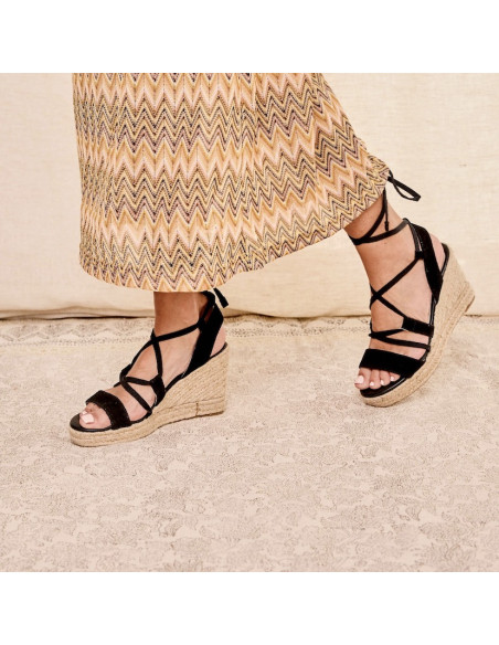 Black leather strap wedge espadrille, perspective view, walking on carpet - MONPIEL Black leather strap wedge espadrille, perspective view, walking on carpet - MONPIEL