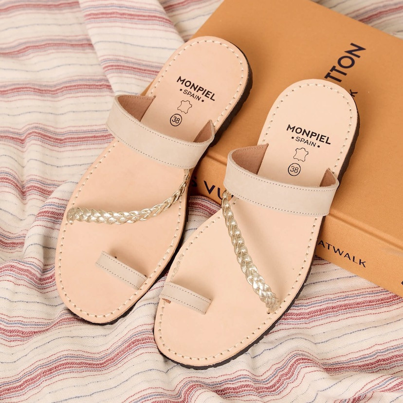 Icy-colored Mykonos Greek leather sandal, front perspective view, resting on a book - MONPIEL