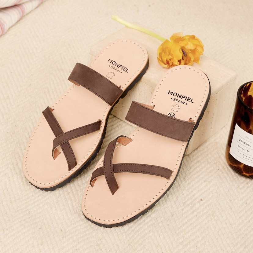 Brown Santorini Greek leather sandal, perspective view, heel resting on a stone - MONPIEL