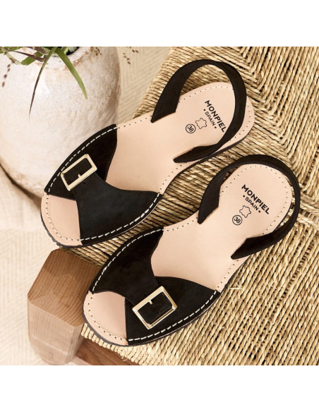 Menorquinische Ledersandalen mit Schnalle in Schwarz, Ansicht von oben, geneigt auf einem Stuhl - MONPIEL Menorquinische Ledersandalen mit Schnalle in Schwarz, Ansicht von oben, geneigt auf einem Stuhl - MONPIEL