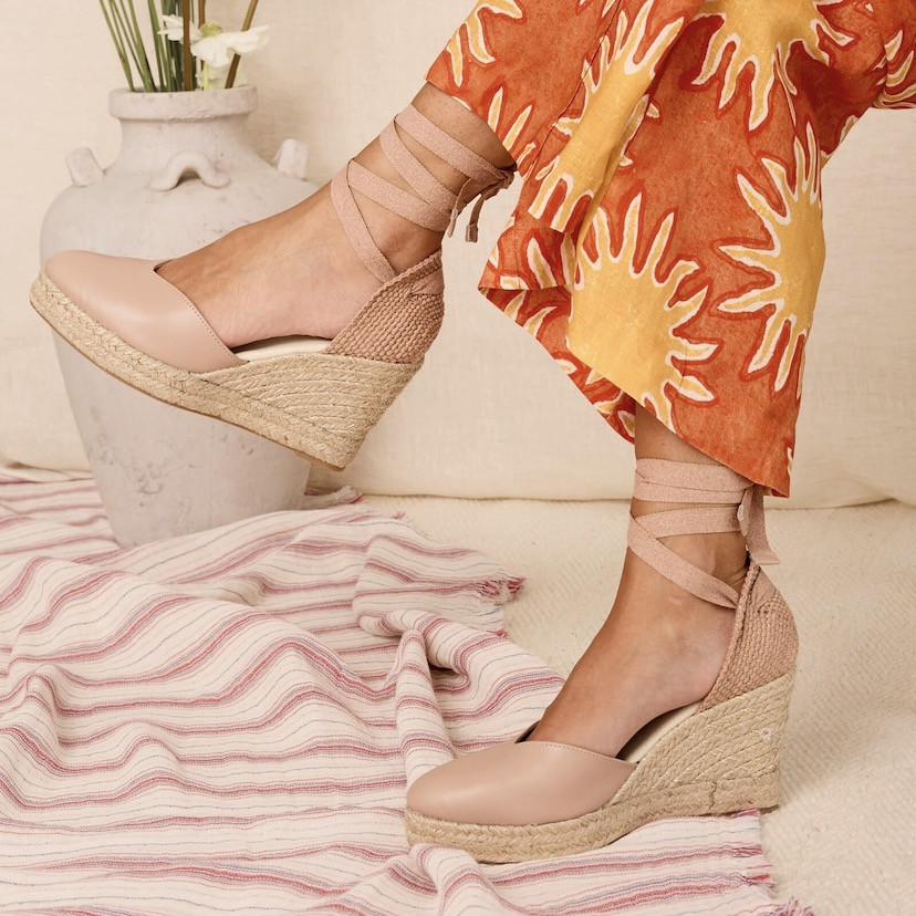 Nude leather Elba wedge espadrille, side view, legs crossed on a carpet - MONPIEL