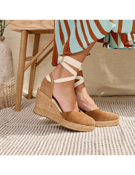Espadrille de couro com cunha Elba em camurça caramelo, vista lateral com os pés apoiados no tapete - MONPIEL Espadrille de couro com cunha Elba em camurça caramelo, vista lateral com os pés apoiados no tapete - MONPIEL
