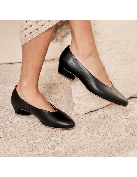 Schwarze Ballerinas mit Absatz, Seitenansicht mit überkreuzten Beinen vor einem Kissen - MONPIEL