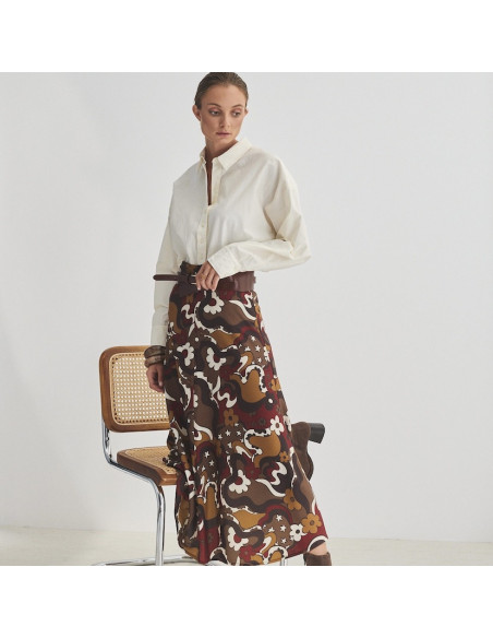 Wide Havana leather belt on a printed skirt, hand resting on the belt - MONPIEL Wide Havana leather belt on a printed skirt, hand resting on the belt - MONPIEL
