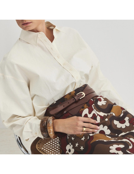 Broad loop belt in havana color with a perspective view, model seated on the chair - MONPIEL