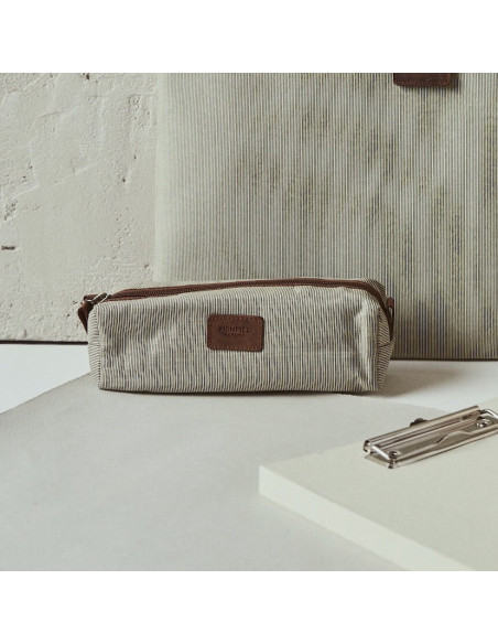 Pencil case in beige color, foreground, resting in front of laptop sleeve - MONPIEL