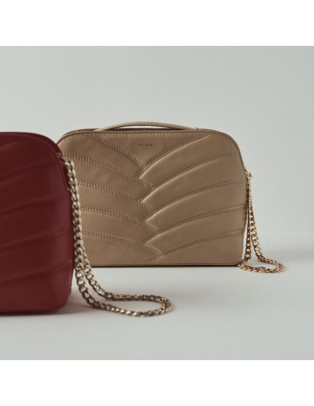 Beige leather quilted bag with gold chain and red in the blurred foreground - MONPIEL Beige leather quilted bag with gold chain and red in the blurred foreground - MONPIEL