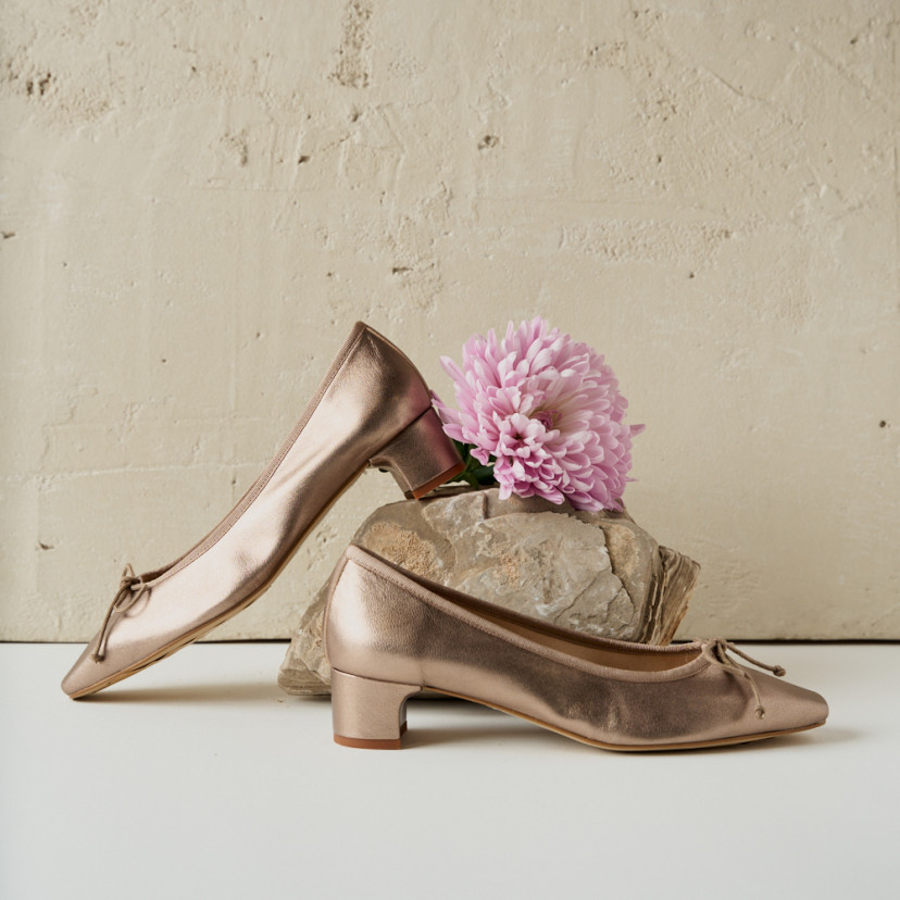 Manuela bow detail kitten heel ballerina in cappuccino bronze, side view, heel resting on rock with flower detail - MONPIEL