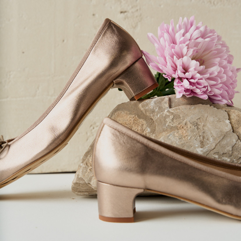 Manuela bow detail kitten heel ballerina in cappuccino bronze, side view, heel resting on rock with close-up flower de - MONPIEL