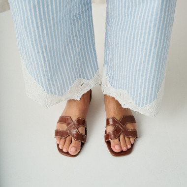 Leather menorquina sandal with buckle in leather colour, perspective view, feet resting on a cushion - MONPIEL 2