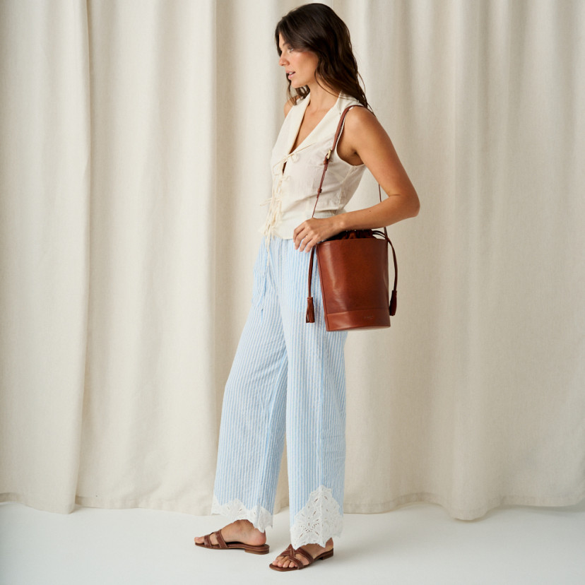 Carmina leather toe-post sandal in coco leather, full shot of model standing sideways with leather bag on shoulder - MONPIEL
