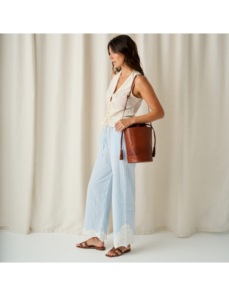 Carmina Ledersandale in Kokoslederfarbe, Gesamtaufnahme eines Models im Profil mit einer Ledertasche auf der Schulter - MONPIEL