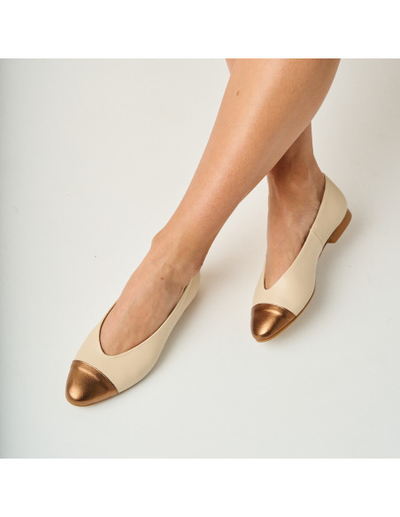 Flache Ameliè-Ballerina mit beige/metallischer Kupferspitze, gekreuzten Füßen im Vordergrund - MONPIEL