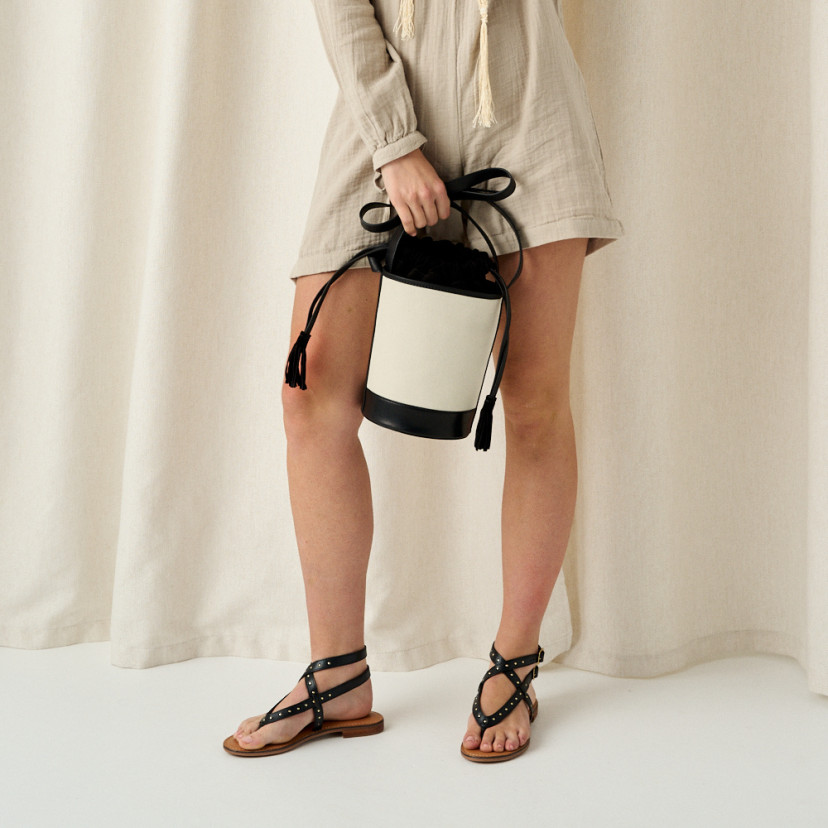 Small black canvas bucket bag held by the handle, front view - MONPIEL