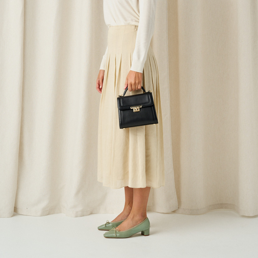 Bolsa de couro pequena estilo 60's para mulheres na cor preta, plano médio com modelo de perfil - MONPIEL
