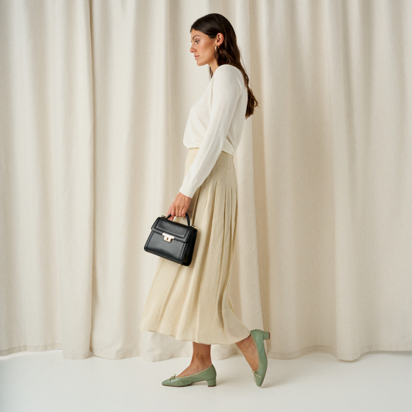 Bolsa de couro pequena feminina estilo 60's em preto, plano geral com modelo de perfil, detalhes dos passos das bailar - MONPIEL