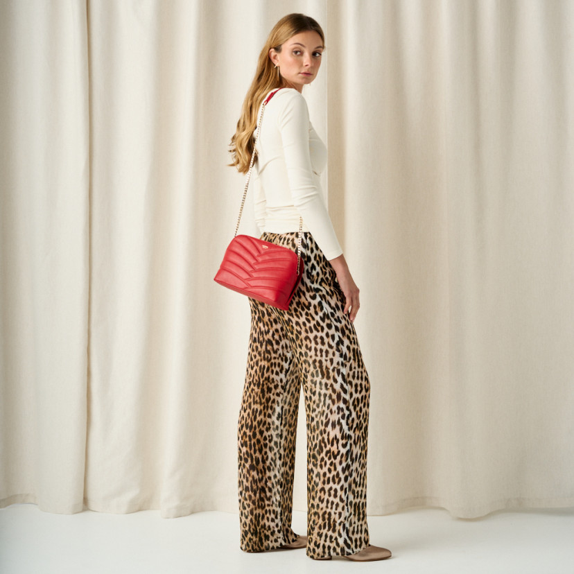 Red leather quilted bag with gold chain, chain hanging on shoulder, full shot of model - MONPIEL