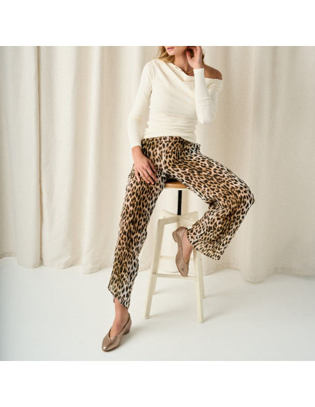 Heeled ballerina shoe in cappuccino bronze color with the model sitting on the stool, wide shot - MONPIEL Heeled ballerina shoe in cappuccino bronze color with the model sitting on the stool, wide shot - MONPIEL