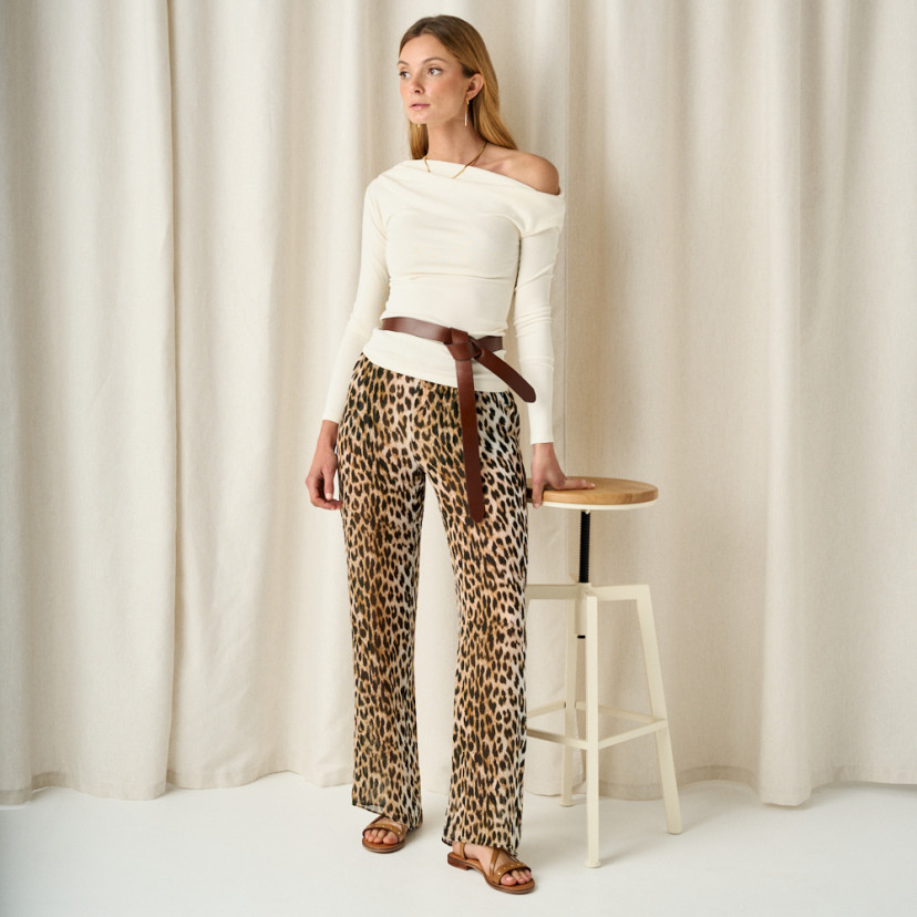 Bari studded cross-strap sandal in leather color, full shot with leather belt at the waist, resting on stool - MONPIEL