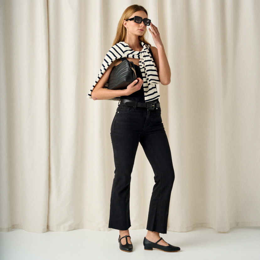 Marieta black leather women's Mary Janes, full-body shot of the model with black leather bag in hand - MONPIEL