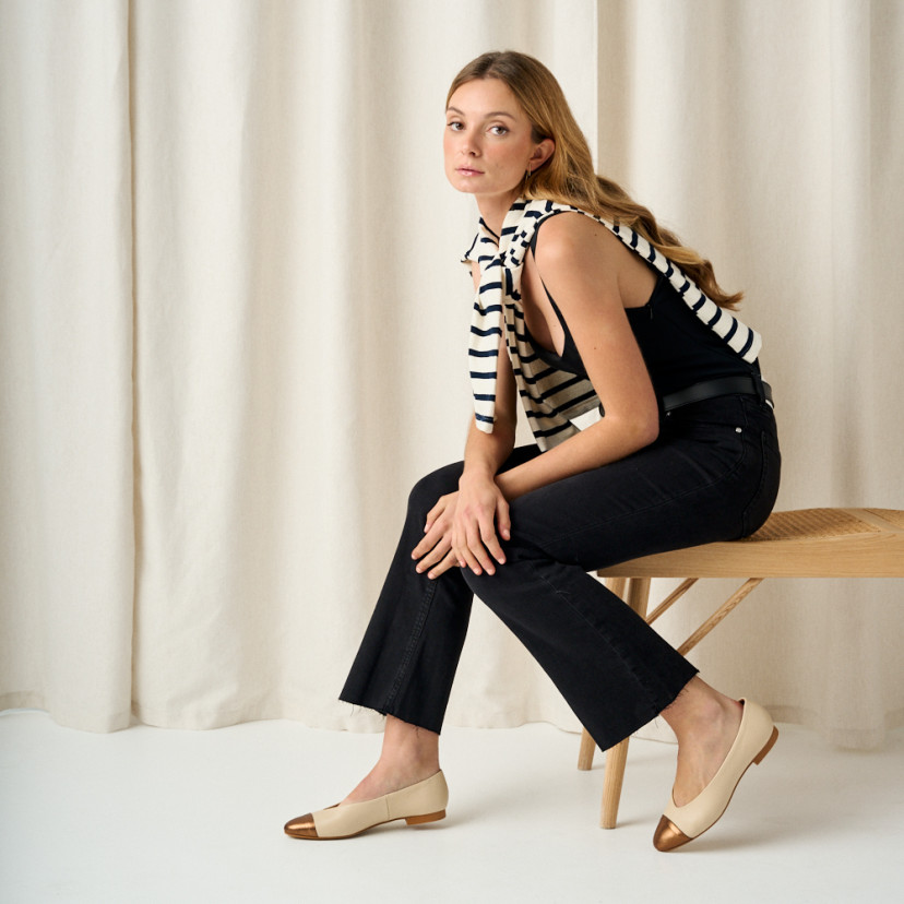 Ameliè flat ballerina with metallic beige/copper toe cap, side view, full-length shot of model sitting on the bench - MONPIEL