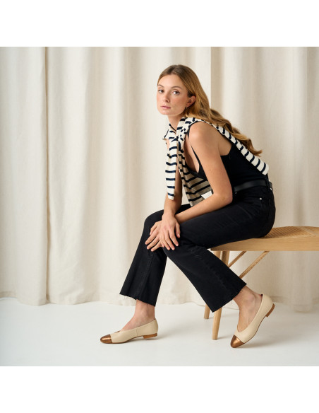 Ameliè flat ballerina with metallic beige/copper toe cap, side view, full-body shot of model sitting on the bench - MONPIEL Ameliè flat ballerina with metallic beige/copper toe cap, side view, full-body shot of model sitting on the bench - MONPIEL
