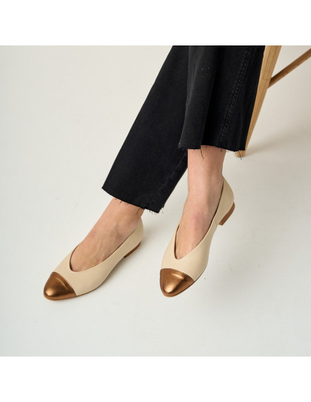 Flache Ameliè-Ballerinas mit beige/kupferfarbenen Metallkappen, überkreuzte Beine im Vordergrund, Perspektivansicht - MONPIEL