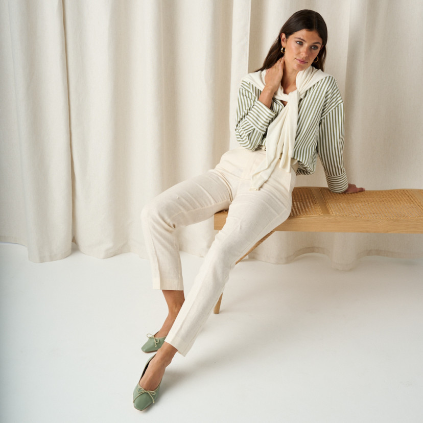 Manuela low heel bow flat slipper in mint green, full shot of the model sitting on the bench with legs stretched out - MONPIEL