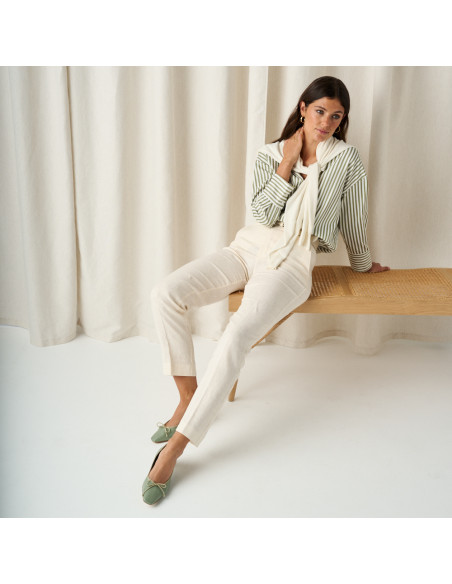 Ballerine à petit talon avec nœud Manuela en vert menthe, plan large de la modèle assise sur le banc avec les jambes a - MONPIEL