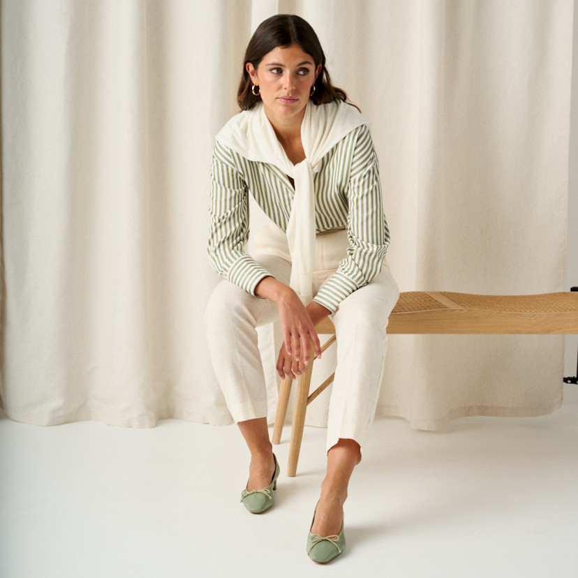 Manuela low heel bow flat slipper in mint green with front view in full shot of the model sitting on the bench with ar - MONPIEL