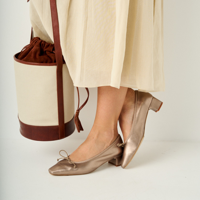 Manuela low heel bow flat slipper in cappuccino bronze with perspective and side view with crossed feet and bucket bag - MONPIEL
