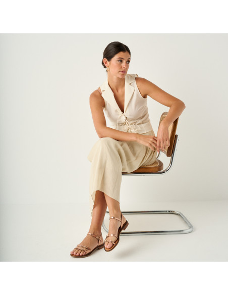 Sandale à boucles Amalfi en or rose, plan général du modèle assis sur la chaise avec les jambes croisées - MONPIEL