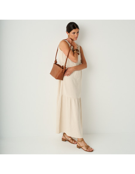 Platinum strap sandal with a small heel in leather color, perspective view in a general shot with a leather bag over t - MONPIEL Platinum strap sandal with a small heel in leather color, perspective view in a general shot with a leather bag over t - MONPIEL