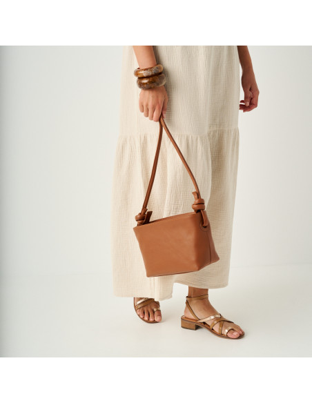 Platinum strap sandal with a small heel in leather color, medium shot with a leather bag hanging - MONPIEL Platinum strap sandal with a small heel in leather color, medium shot with a leather bag hanging - MONPIEL