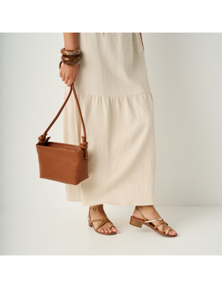 Platinum strap sandal with a small heel in leather color, medium shot with a leather bag hanging - MONPIEL Platinum strap sandal with a small heel in leather color, medium shot with a leather bag hanging - MONPIEL