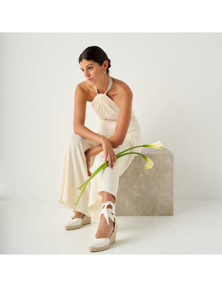 Espadrilla Elba in seta per sposa color bianco con vista in prospettiva, piano generale del modello seduto su un cubo - MONPIEL