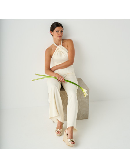 Espadrilla con zeppa nudo Lyra color platino in piano generale del modello seduto su un cubo di marmo con un fiore in - MONPIEL