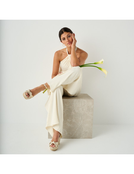Lyra wedge espadrille with knot in platinum in full shot of the model sitting on marble cube with crossed leg - MONPIEL Lyra wedge espadrille with knot in platinum in full shot of the model sitting on marble cube with crossed leg - MONPIEL