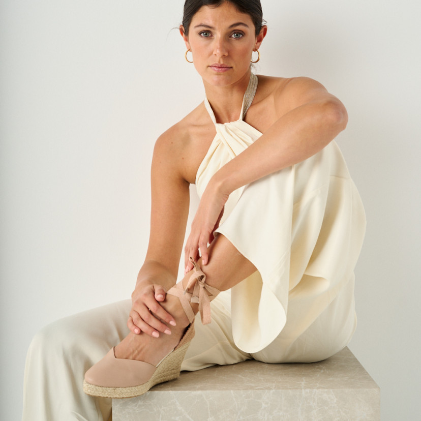 Espadrilha de cuña Elba de couro na cor nude, com modelo sentada sobre cubo de mármore e pé apoiado - MONPIEL