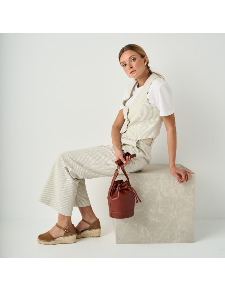 Espadrille à talon compensé média Menorca couleur vison, vue de profil, plan général avec un sac en cuir à la main - MONPIEL