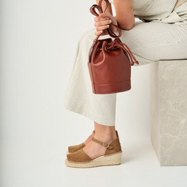 Borsa secchiello piccola in pelle color cuoio, vista frontale, accanto a un vaso - MONPIEL 2